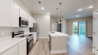 Located at 2901 Corporate Exchange Dr in Columbus, OH, this thoughtfully designed one-bedroom, one-bathroom unit offers a functional and modern living experience across a single floor. The open-concept layout seamlessly connects the kitchen and living room, creating a bright, cohesive space ideal for both daily living and entertaining. Light wood-style flooring flows throughout the main living areas, enhancing the clean, contemporary aesthetic.

The kitchen is a standout feature, equipped with crisp white shaker-style cabinetry, white quartz countertops, and a full suite of stainless steel appliances including a refrigerator, range, and microwave. A center island with pendant lighting and an integrated sink serves as a practical focal point, adding both style and functionality.

The living room offers access to a private balcony through a sliding glass door, allowing for natural light and outdoor views. The bedroom is carpeted for comfort, features large windows that bring in ample natural light, a ceiling fan, and direct access to a spacious walk-in closet outfitted with wire shelving systems for efficient storage organization. The bathroom includes a full tub and shower combination with clean white finishes. Light-toned walls and neutral finishes throughout give the space a calm, modern ambiance.