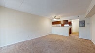 This single-floor unit at 2905 Parklane St NW in Canton, Ohio offers a functional, open-concept layout designed for comfortable everyday living. The spacious living area is finished with wall-to-wall carpet in a neutral tone, creating a warm and inviting atmosphere. A ceiling fan with integrated lighting serves as a central fixture, providing both airflow and illumination. Large sliding glass doors dressed with vertical blinds allow natural light to fill the room while offering access to the exterior.

The kitchen is positioned adjacent to the living area and separated by a half-wall pass-through with an upper wood-toned cabinet, creating a natural division while maintaining an open feel. Inside, the kitchen features rich dark wood cabinetry, granite-style laminate countertops, tile flooring, and white appliances including a range, refrigerator, and dishwasher. A stainless steel sink is set beneath upper cabinets, maximizing storage and workspace throughout.

The bathroom is finished in a clean, all-white palette, featuring a single-sink vanity with white cabinetry, a large mirror, and a tub-shower combination. Over-the-toilet cabinetry adds practical storage, while tile flooring completes the space with a durable, polished look. Overall, the unit presents a straightforward and well-maintained layout suited for efficient single-floor living.