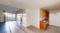 This single-floor residence showcases a clean, contemporary design throughout. Light hardwood-style flooring extends seamlessly across all living areas, contributing to a bright and cohesive aesthetic. The open layout connects the main living space to the kitchen, which is a standout feature of the unit. The kitchen is equipped with rich warm-toned wood cabinetry on both upper and lower levels, stainless steel countertops, a built-in sink, and premium stainless steel appliances including a professional-grade range and refrigerator, all accented by recessed lighting overhead.

The living area benefits from generous natural light, with large floor-to-ceiling sliding glass doors opening onto a private balcony that offers expansive elevated views of the surrounding area. The louvered interior doors add a distinctive architectural detail throughout.

The bedrooms are bright and well-proportioned, each featuring the same light flooring and clean white walls. One bedroom provides direct access to abundant natural light through a large window. The bathroom is finished with warm wood vanity cabinetry, a wide mirror, a combination tub and shower with glass sliding doors, and contemporary fixtures, completing this well-designed and functional living space.