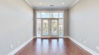 Located at 1308 Lorna St, Unit 406 in Charlotte's 28205 zip code, this one-bedroom, one-bathroom unit offers a well-designed layout across a single floor. The open-concept kitchen and living room serves as the heart of the home, featuring rich hardwood flooring, crown molding, and recessed lighting throughout. The kitchen is appointed with white shaker-style cabinetry extending to the ceiling, dark quartz countertops, a mosaic tile backsplash, stainless steel appliances including a French door refrigerator and range with a sleek hood vent, and pendant lighting over a breakfast bar. The living area is bathed in natural light from large French doors that open to a private balcony with views of the surrounding greenery. The bedroom is comfortably sized with soft carpeting, a large window offering outdoor views, and a tray ceiling detail. It connects to a walk-in closet equipped with wire shelving. The full bathroom features a double-sink vanity with dark countertops, framed mirrors, a glass-enclosed walk-in shower with marble-style tile, and elegant tilework underfoot. A hallway connects all areas, completing this thoughtfully arranged urban residence.