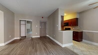 This single-floor residence offers a thoughtfully arranged layout that balances functionality and comfort throughout its living spaces. The open-concept living and dining area is finished with durable wood-style plank flooring, neutral taupe walls, and a ceiling fan, creating a welcoming atmosphere. A window dressed with sheer curtains allows natural light to filter in, while a peninsula counter visually connects the living area to the kitchen.

The galley-style kitchen is well-appointed with rich cherry wood cabinetry, granite countertops, and a full suite of black appliances, including a gas range, built-in microwave, and refrigerator. A tile backsplash adds visual texture, and light ceramic tile flooring completes the space. The kitchen's efficient corridor layout maximizes storage and workspace on both sides.

The bedrooms are carpeted for comfort and feature neutral tones consistent with the rest of the unit. Each room includes generous closet space, with mirrored sliding-door closets providing added storage and a sense of depth. Windows with blinds bring in natural light. The bathroom is finished with ceramic tile flooring and connects conveniently to the bedroom corridor. Overall, the space presents a clean, functional design with cohesive finishes throughout.