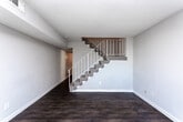 Located at 2280 Campbellton Rd SW in Atlanta, Georgia, this two-story property offers a practical and well-organized layout across both levels. The main floor features dark hardwood-style flooring throughout the living and dining areas, creating a cohesive and clean aesthetic. A chandelier with candelabra-style lighting anchors the dining area, which also includes vertical blinds along a sliding door that allows natural light to filter in. The kitchen is equipped with white cabinetry, a white electric range, a refrigerator, a sink with granite-style countertops, and a textured ceiling, providing ample storage and workspace. A staircase with a decorative railing connects the two floors, as visible in the dollhouse overview. The upper level transitions to carpeted bedrooms, each featuring neutral-toned walls, standard closets with built-in shelving, ceiling-mounted light fixtures, and windows with horizontal blinds that offer views of the surrounding greenery. The bathroom includes white tile flooring, a tiled shower-tub combo, and a toilet. Throughout the property, the neutral color palette and consistent finishes contribute to a functional, move-in-ready environment suited for everyday living.