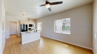 This efficiently designed single-floor unit offers a bright and functional open-concept layout that seamlessly combines the kitchen and living area into one cohesive space. Light wood-tone laminate flooring runs throughout, lending warmth and visual continuity across every room.

The kitchen is outfitted with light natural wood cabinetry, white countertops, and a full suite of black Whirlpool appliances, including a refrigerator, electric range, over-the-range microwave, and dishwasher. A central island with an integrated sink provides additional prep space and a casual gathering point. Multiple windows fitted with horizontal blinds allow natural light to fill the kitchen and living area, creating an airy, open ambiance.

The living area is spacious relative to the unit's footprint, featuring a ceiling fan with an integrated light fixture, a wall-mounted HVAC unit, and a glass door leading to an outdoor area. The neutral gray walls complement the light flooring, producing a clean, modern aesthetic throughout.

The bathroom continues the light and minimal design language, featuring the same wood-tone flooring, a window for natural light, and a shower with a curtain enclosure. The unit also includes an electrical panel conveniently located within the living space. Overall, the unit presents a well-appointed, functional layout with a cohesive modern design.