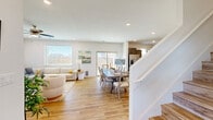 This two-story home offers a well-organized layout spread across two floors, with the main level housing the primary living spaces and the upper level accommodating the majority of the bedrooms and bathrooms. Light-toned hardwood flooring runs throughout, complementing the bright, neutral color palette that gives the home a clean, airy feel.

The main floor opens into a combined living, dining, and kitchen area. The living room features recessed lighting, a large window with outdoor views, and a sliding glass door that connects to the backyard patio. The kitchen is a standout feature, equipped with dark gray shaker-style cabinetry, stainless steel appliances, white subway tile backsplash, and a large granite-topped island with bar seating. A separate dining area provides additional space for meals. Two dedicated office rooms add functional versatility to the layout.

Upstairs, five bedrooms include a spacious primary suite with a walk-in closet featuring dual hanging rods and upper shelving, and an ensuite bathroom with gray cabinetry, granite countertops, and a glass-enclosed shower. Additional bedrooms are well-proportioned with ample natural light. A dedicated laundry area houses a full-size washer and dryer with overhead shelving, completing the upper floor's practical amenities.