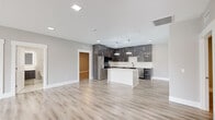 This well-appointed single-floor residence offers four bedrooms, two bathrooms, and a thoughtfully designed layout that maximizes space and functionality. The open-concept kitchen and living area serves as the heart of the home, showcasing light wood-tone flooring throughout, crisp neutral walls, and abundant recessed lighting. The contemporary kitchen is outfitted with dark wood-grain cabinetry, stainless steel appliances, a white marble-veined quartz island, a subway tile backsplash, and striking circular pendant lights that add a refined touch. The primary bedroom is generously sized, featuring a ceiling fan, a large window with scenic open landscape views, and access to well-organized closets equipped with wire shelving systems. Additional bedrooms are bright and comfortable, with one offering sliding glass door access to a private balcony overlooking open outdoor scenery. The bathrooms are finished to a high standard, with the primary bath showcasing large-format marble-look tile on both the floors and walk-in shower walls, a floating vanity with an illuminated LED mirror, and chrome fixtures. Three closets and a dedicated utility room provide ample storage throughout. The overall aesthetic is clean, modern, and move-in ready.