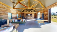 Located at 3144 Old Franklin Road in Antioch, TN, this single-story community clubhouse delivers a striking blend of rustic charm and modern amenity. The exterior features bold red barn-style sliding doors with classic cross-buck detailing, setting the tone for the warm, inviting interior within.

Inside, the open-plan space is defined by soaring vaulted ceilings supported by prominent exposed natural wood trusses and beams. Reclaimed wood planking covers every wall, creating a cohesive, lodge-inspired aesthetic throughout. Polished concrete floors provide a clean, durable foundation that complements the organic textures above.

The main gathering area is generously proportioned, accommodating a variety of recreational and social uses. A dedicated lounge zone features comfortable seating, while a ping-pong table and a full-length shuffleboard table provide ample entertainment options. A bar area with bar-height seating and a wall-mounted television anchors one end of the space, ideal for social gatherings.

Natural light pours in through multiple windows and large doorways, offering views of the surrounding landscaped grounds. Outside, a fenced pool area with lounge seating, patio umbrellas, and ornamental grasses creates an inviting outdoor retreat. A fire pit area and walking paths further enhance the outdoor experience, making this clubhouse a comprehensive community amenity.