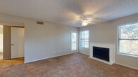 This single-floor residence offers a thoughtfully designed layout that balances comfort and functionality. The living room serves as the centerpiece of the home, featuring warm neutral-toned carpet, a classic white-framed fireplace, and multiple windows fitted with blinds that allow natural light to fill the space. A ceiling fan with integrated lighting provides year-round comfort, while textured ceilings add a traditional character throughout.

The open entry area connects seamlessly to both the living room and a dedicated dining space, the latter highlighted by a pendant light fixture. A pass-through opening links the dining area to the kitchen, enhancing the sense of flow between rooms.

The galley-style kitchen is well-equipped, showcasing crisp white cabinetry with modern hardware, light granite-style countertops, a subway tile backsplash, and a full suite of black appliances including a range, refrigerator, and dishwasher. Wood-look flooring grounds the kitchen and extends into the bathroom.

The bathroom features a full soaking tub with tiled surround and a curved shower rod, complemented by durable wood-look plank flooring. The bedroom is generously sized with plush carpet, a ceiling fan, and a sliding glass door that opens to a private balcony overlooking a natural, tree-lined setting.
