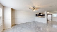 Located at 1080 Vineyard Loop in Iowa, Louisiana, this two-story home offers a well-organized layout across two floors. The main level is anchored by a spacious open-concept living, dining, and kitchen area finished with polished concrete floors that lend a clean, modern feel. Ceiling fans provide comfort throughout, while wainscoting-style wall detailing adds a subtle architectural touch. The kitchen is equipped with dark wood cabinetry, ample counter space, white appliances including a range and refrigerator, and a peninsula that separates it from the living and dining areas. A half bath with a pedestal sink is also conveniently located on the main floor. A staircase leads to the upper level, which houses both bedrooms, including a generously sized primary bedroom, along with additional bathrooms featuring matching dark cabinetry and light-toned finishes. Three closets provide practical storage throughout. The upper floor also includes a dedicated laundry area and a hallway connecting the rooms. Light speckled flooring carries through the upper level, maintaining a bright and neutral palette. A covered patio extends the living space outdoors, rounding out this efficiently designed two-story home.
