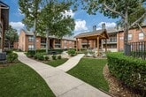 This contemporary apartment in Webster, Texas offers 750 square feet of thoughtfully designed living space. The unit features two bedrooms, including a spacious primary bedroom of 210 square feet, and two full bathrooms. The open-concept living area showcases a modern fireplace with a sleek white surround, creating a focal point for relaxation and entertainment. Large sliding glass doors flood the space with natural light and provide access to outdoor views.

The kitchen boasts updated stainless steel appliances, white cabinetry, and ample counter space, perfect for culinary enthusiasts. Durable wood-look flooring runs throughout the main living areas, while plush carpeting adds comfort to the bedrooms. The bathrooms feature clean lines with white fixtures and vanities.

Storage is abundant, with a walk-in closet offering built-in shelving and a separate laundry area for convenience. Ceiling fans in the bedrooms provide additional comfort. The neutral color palette throughout creates a versatile canvas for various decorating styles. This well-appointed apartment combines functionality and style, offering a cozy yet modern living experience in a prime location.