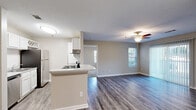 Located at 4801 Baker Grove Rd NW in Acworth, GA, this 2-bedroom, 2-bathroom residence offers a well-designed single-floor layout that maximizes functionality and comfort. The open-concept living and kitchen area serves as the heart of the home, featuring durable wood-style plank flooring, neutral warm-gray walls, and a ceiling fan that enhances airflow throughout the space. The kitchen is equipped with white cabinetry, a subway tile backsplash, stone-look countertops, and black stainless appliances including a range, refrigerator, and dishwasher. A peninsula countertop provides additional prep space and casual seating. The living room is bathed in natural light through multiple windows and a sliding glass door fitted with vertical blinds, offering outdoor access and views of the surrounding area. Both bedrooms are generously sized, featuring plush carpeting, multiple windows with blinds for natural light and privacy, and dedicated closet space. The two bathrooms are finished with white vanities, stone-look countertops, and clean tile surrounds in the tub-shower combinations. The textured ceilings and clean white trim throughout add a crisp, polished finish to this well-appointed home.