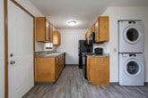 Located at 624 S Oak St in Mount Pleasant, Michigan, this two-floor unit offers a practical and functional layout spread across two levels. The main level features durable hardwood-style flooring throughout its open living areas, which are kept bright by natural light filtering through blinds-equipped windows. A private entry door with warm wood trim frames the welcoming entryway. The galley-style kitchen is efficiently designed with honey-toned wood cabinetry, granite-patterned countertops, a double basin sink, and black appliances including a refrigerator, electric range, microwave, and dishwasher. A half bathroom with a wall-mounted sink is conveniently accessible on the main floor. A wood-railed staircase connects the two levels, leading to the upper floor where multiple carpeted bedrooms each feature their own windows for natural light and floor vents for climate control. One bedroom includes a walk-in closet with built-in shelving. The upper level is served by a full bathroom complete with a vanity featuring a wood cabinet, a well-lit mirror, and a tub/shower combination. Consistent warm wood trim and neutral wall tones create a cohesive, understated aesthetic throughout the space.