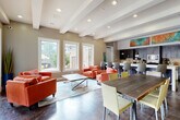 Located in Atlanta, GA, this single-story community clubhouse on Peachwood Circle NE offers a well-appointed gathering space designed for both relaxation and productivity. The open-plan layout is anchored by polished concrete floors that flow throughout the main areas, lending an industrial-modern character to the overall design.

The social lounge area is bright and welcoming, featuring exposed beam ceilings with recessed lighting, large windows, and full-length glass doors that open directly to an outdoor pool patio. Vibrant coral seating arrangements and a sleek coffee table sit atop a patterned area rug, creating a comfortable setting for casual gatherings.

The fully equipped kitchen is a standout feature, showcasing dark cabinetry, granite countertops, a stone tile backsplash, and stainless steel appliances including a wall oven, microwave, and beverage refrigerator. A large granite-topped island provides ample bar seating, while bold abstract artwork displayed above the cabinetry adds a lively, artistic touch.

A dedicated workspace area features a vaulted ceiling, warm wood-panel accent walls, built-in desks, and a wall-mounted TV, making it ideal for focused work or small meetings. The space is completed by a separate private office with rich wood wall paneling and hardwood flooring, offering a quiet retreat within the facility.