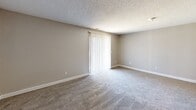 Located at 513 E. Marion Rd in Wichita, Kansas, this one-bedroom, one-bathroom unit offers a practical and comfortable layout across a single floor. The combined kitchen and living area forms the heart of the home, where wood-look flooring in the kitchen transitions into soft carpeting in the living space. The kitchen features warm honey-toned cabinetry, a white electric range, a full-size refrigerator, and a peninsula with granite-look countertops that doubles as a casual dining or prep surface. A textured ceiling runs throughout the unit, lending a consistent finish to each room. The living area is bright and open, highlighted by a full-width sliding glass door dressed with vertical blinds that allows natural light to fill the space and provides access to the outdoors. The bedroom offers comfortable proportions, wall-to-wall carpet, a natural light source through a window, and the added convenience of two closets for generous storage. The bathroom is straightforward and functional, equipped with a full tub-shower combination and overhead cabinetry for additional storage. Neutral wall tones and carpet throughout create a clean, move-in-ready environment well-suited for low-maintenance living.