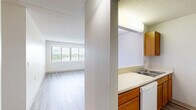 Located at 901 E Como Blvd in Saint Paul, Minnesota, this single-floor unit offers three bedrooms and one bathroom within a efficiently arranged floor plan. The layout, visible in the dollhouse view, centers around a combined kitchen and living area that serves as the heart of the home. The kitchen features warm-toned wood cabinetry, light countertops, a double-basin sink, and white appliances including a refrigerator, dishwasher, and electric range — all set atop durable wood-look flooring that carries into the living area. The spacious living room benefits from a large picture window fitted with horizontal blinds, allowing ample natural light and views of the surrounding neighborhood. The three bedrooms are carpeted for comfort, with neutral gray tones and clean white walls creating a calm, functional atmosphere. Several bedrooms include warm-wood sliding closet doors for storage, and windows throughout provide continued outdoor views. The bathroom is equipped with a full tub and shower combination, grab bars for accessibility, mosaic tile flooring, and a clean white finish. The unit's straightforward, practical design makes efficient use of its footprint, offering a comfortable and functional living environment.
