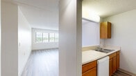 Located at 901 E Como Blvd in Saint Paul, Minnesota, this single-floor unit offers three bedrooms and one bathroom within a efficiently arranged floor plan. The layout, visible in the dollhouse view, centers around a combined kitchen and living area that serves as the heart of the home. The kitchen features warm-toned wood cabinetry, light countertops, a double-basin sink, and white appliances including a refrigerator, dishwasher, and electric range — all set atop durable wood-look flooring that carries into the living area. The spacious living room benefits from a large picture window fitted with horizontal blinds, allowing ample natural light and views of the surrounding neighborhood. The three bedrooms are carpeted for comfort, with neutral gray tones and clean white walls creating a calm, functional atmosphere. Several bedrooms include warm-wood sliding closet doors for storage, and windows throughout provide continued outdoor views. The bathroom is equipped with a full tub and shower combination, grab bars for accessibility, mosaic tile flooring, and a clean white finish. The unit's straightforward, practical design makes efficient use of its footprint, offering a comfortable and functional living environment.
