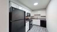 Located at 5020 Chatterton Rd in Columbus, Ohio, this single-floor unit offers a practical and well-maintained layout designed for comfortable everyday living. The kitchen is a standout feature, outfitted with crisp white shaker-style cabinetry, dark granite-look countertops, and wood-look plank flooring. Black appliances — including a gas range, over-the-range microwave, refrigerator, and dishwasher — provide a sleek contrast to the bright cabinetry. A stainless steel double-basin sink with a modern faucet completes the functional workspace. The living area is generously sized, finished with neutral carpet and soft gray walls, and benefits from natural light through multiple windows. The bedrooms continue the consistent neutral palette, with plush carpet underfoot; one bedroom features a ceiling fan and closet, while another includes a sliding closet and direct hallway access. The bathroom is clean and efficiently arranged, with a white vanity, a full tub and shower surround, wood-look tile flooring, and brushed nickel fixtures throughout. The overall layout, visible in the dollhouse view, flows logically between the living, sleeping, and kitchen areas, creating a cohesive and easy-to-navigate living environment.