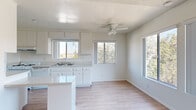 Located at 241 Avocado St in Costa Mesa, CA, this single-story 1-bedroom, 1-bathroom home offers a well-organized layout across a compact but functional floor plan. The open-concept kitchen and living area forms the heart of the home, bathed in natural light from multiple sliding windows that frame views of the surrounding neighborhood. The kitchen features white cabinetry, a peninsula island with counter seating, a gas range, dishwasher, refrigerator, and a stainless steel sink — all finished in a clean, neutral palette. A ceiling fan with light fixture anchors the living area, contributing to comfortable airflow throughout. Light wood-style flooring runs seamlessly through the main living spaces and into the bedroom, lending a cohesive, bright aesthetic. The spacious primary bedroom includes a large closet and a window with neighborhood views, offering a quiet and well-lit retreat. The full bathroom is finished in white tile, with a single-sink vanity, large mirror, and a tub/shower combination with a window above for natural ventilation. Textured ceilings are present throughout. A hallway connects the main living areas to the private spaces, completing the efficient and practical layout of this Costa Mesa home.