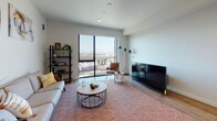 Located at 1225–1243 5th St in Oakland, CA, this modern single-floor residence offers a well-designed open-concept layout with clean lines and contemporary finishes throughout. The living area is bright and welcoming, anchored by large floor-to-ceiling windows that flood the space with natural light and frame panoramic views of the Oakland cityscape. Warm hardwood-style flooring runs throughout, complementing the neutral color palette and creating a cohesive, airy atmosphere.

The kitchen is efficiently designed with modern flat-front cabinetry in a light wood and gray finish, stainless steel appliances including a gas range, microwave, and dishwasher, and ample upper and lower cabinet storage. A built-in storage tower provides additional organizational space, making the kitchen both functional and visually streamlined.

The bedroom is a calm, private retreat with access to natural light and views of the surrounding area. Adjacent to the bedroom, the full bathroom features a soaking tub with a tiled surround, a clean white toilet, and a wall-mounted sink, all set on neutral tile flooring for a polished, understated look.

Throughout the unit, recessed lighting ensures consistent illumination, and the open flow between the kitchen and living area makes the space feel generously proportioned and ideal for everyday living.