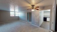 Located at 6725 Ramblewood Dr in Fort Wayne, Indiana, this single-floor home offers a straightforward and functional layout with consistent design choices throughout. The living area is carpeted and finished with neutral gray walls, a textured popcorn ceiling, and a ceiling fan with integrated lighting, creating a comfortable and well-ventilated space. A wall-mounted thermostat and HVAC vent are conveniently positioned, and windows allow natural light to fill the room.

The bedrooms are carpeted and feature the same neutral wall tones and textured ceilings. One bedroom includes a built-in open shelving closet, a ceiling fan, and access to an additional room, while another bedroom offers a dedicated closet and a window with outdoor views, providing a bright and airy feel.

The kitchen is well-equipped with white cabinetry, dark countertops, and black appliances including an electric range, dishwasher, and range hood. A stainless steel sink is set beneath a window, and wood-look flooring ties the space together cleanly.

The bathroom is neatly appointed with a white vanity, mirror with built-in lighting, a toilet, and a tub and shower combination enclosed by a decorative curtain. Wood-look flooring continues here, maintaining visual consistency with the kitchen. Overall, the home presents a clean, move-in ready environment with practical features throughout.