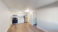 This single-floor unit offers a clean, modern aesthetic with a practical and efficient layout. The open-concept living and kitchen area is finished with light wood-tone luxury vinyl plank flooring that runs throughout, creating a cohesive and easy-to-maintain interior. Neutral gray walls and white trim provide a bright, contemporary backdrop across all rooms.

The kitchen is thoughtfully designed with white shaker-style cabinetry, a stainless steel electric range, stainless steel refrigerator, and an undermount sink. A range hood above the stove and ample upper and lower cabinet storage round out the functional cooking space.

The living area is open and airy, benefiting from a large window beside the front entry door that allows natural light to fill the space. A wall-mounted HVAC unit provides individual climate control. The entry features a solid panel door with a keypad lock for added security.

The bedroom is a quiet, dedicated space with its own window overlooking an exterior stairway, providing natural light and ventilation. The bathroom is clean and straightforward, featuring a full tub and shower combo with white tile surround, a toilet, and a vanity sink. Overall, the unit presents a well-maintained, move-in-ready interior with consistent modern finishes.