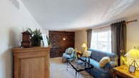 This two-floor home offers a warm and inviting atmosphere defined by classic design elements and comfortable living spaces. The upper level features a bright living room highlighted by a striking exposed brick accent wall, large windows that bring in natural light, and plush carpeting underfoot. A well-appointed kitchen on this level includes oak cabinetry, a gas range, dishwasher, and a double basin sink — all efficiently arranged for everyday use. A charming half bathroom on this floor is distinguished by patterned wallpaper and decorative accents, adding a touch of personality.

The lower level expands the living space considerably, featuring an open layout that connects a second living area with a dining space, separated by a structural column. Carpeted throughout, this floor is accessible via a carpeted staircase with a wrought iron railing. Two bedrooms are located on this level — one featuring a sliding glass door that opens to an outdoor view, and both equipped with ceiling fans and ample natural light. A full bathroom with tub-shower combination and bold patterned wallpaper completes this floor. Throughout the home, the interplay of natural textures, warm tones, and thoughtful details creates a cohesive and welcoming residential environment.
