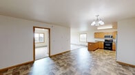 Located at 39th Ave SE in Minot, North Dakota, this single-floor, 3-bedroom, 2-bathroom home offers a well-organized and functional layout across a comfortably sized footprint. The open-concept kitchen and dining area serves as the heart of the home, featuring warm honey-toned wood cabinetry, generous counter space, a central peninsula, stainless steel appliances including a refrigerator, dishwasher, and over-the-range microwave, complemented by durable tile-style flooring. A pendant chandelier adds a finishing touch above the dining area. The living room is spacious and bright, with multiple windows framing outdoor views and direct access to the outdoors through a glass door, filling the room with natural light. Plush carpeting and baseboard heating run throughout the bedrooms, which are well-proportioned and include ample closet storage across four closets. The bathrooms are clean and functional, featuring a full tub-shower combination with white tile surround. A dedicated in-unit laundry room houses a full-size washer and dryer. Neutral wall tones, warm wood trim, and consistent finishes throughout give the home a cohesive and inviting character well-suited to comfortable everyday living.