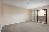 Located at 2300 Fairview Rd in Costa Mesa, California, this multi-floor residence offers 2 bedrooms and 3 bathrooms within a well-organized layout. The unit is part of a three-story building that includes covered ground-level parking, providing convenient and protected vehicle storage.

The living room features neutral beige walls, soft carpeting, and a textured ceiling with a ceiling fan, creating a comfortable and functional common area. An entry door opens directly into this space, which flows toward the kitchen and additional rooms. The galley-style kitchen is outfitted with white cabinetry, light countertops, a stainless steel sink, and an electric range, all set atop wood-look flooring that adds a clean, practical touch.

Both bedrooms are carpeted and feature mirrored sliding closet doors that enhance the sense of space. The generously sized primary bedroom includes built-in shelving for additional storage. The bathrooms are straightforward and functional, each featuring a tub-shower combination with clean white surrounds and brushed nickel fixtures.

A hallway connects the main areas and includes a built-in linen closet with multiple shelves, maximizing storage throughout. The warm, neutral color palette used consistently across the unit lends a cohesive and inviting ambiance throughout the home.