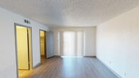 Located at 6008 White Dove Dr in Fort Worth, TX, this single-story unit offers a practical and well-organized layout designed for comfortable everyday living. The open living area features light wood-style laminate flooring and clean white walls, creating a bright and neutral backdrop. A textured ceiling runs throughout the space, and vertical blinds along a sliding glass door allow natural light to filter into the main living area. The kitchen is efficiently laid out in a galley-style configuration, featuring gray cabinetry, light countertops, a black electric range, a stainless steel over-the-range microwave, a black refrigerator, and a double-basin sink — providing all the essential appliances in a compact, functional space. The bedroom is generously proportioned, with wood-style flooring, a textured ceiling, and a sliding glass door fitted with vertical blinds that let in ample natural light. A walk-in closet is accessible directly from the bedroom, offering practical storage. The bathroom includes a single-sink vanity with a mirrored medicine cabinet, overhead lighting, and a combined tub and shower. HVAC vents are visible throughout, ensuring climate control across the unit. Overall, the space presents a clean, move-in-ready environment with consistent finishes throughout.
