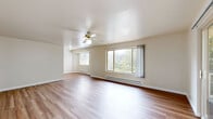 Located in Seattle, WA, this well-appointed 2-bedroom, 1-bathroom residence offers a practical and comfortable single-floor layout. The open living room is a welcoming space highlighted by warm wood-style flooring, a ceiling fan, and a large window that frames views of surrounding greenery, filling the room with natural light. Baseboard heating throughout ensures year-round comfort.

The kitchen is efficiently designed with warm honey-toned wood cabinetry, stone-finish countertops, a white electric range, dishwasher, and an under-cabinet ventilation hood — providing all the essentials for everyday cooking.

Both bedrooms feature plush carpeting and dark-toned sliding closet doors that provide generous storage. The primary bedroom is notably spacious, offering dual closets and a window with outdoor views, while the second bedroom is equally comfortable with its own closet. A connecting hallway links the bedrooms to the shared full bathroom, which features a clean white soaking tub-shower combination and a bright frosted window.

The overall aesthetic is clean and neutral throughout, with light-toned walls and consistent finishes creating a cohesive, move-in-ready atmosphere across the entire residence.