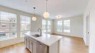 Located at 700 E. Long St. in Columbus, OH, this thoughtfully designed 2-bedroom, 2-bathroom single-floor residence offers a clean, modern aesthetic throughout. Light hardwood flooring runs continuously across the entire unit, tying each space together seamlessly.

The open-concept kitchen and living area serves as the heart of the home. The kitchen is equipped with stainless steel appliances, gray shaker-style cabinetry, a white subway tile backsplash, and a spacious white waterfall island with an integrated sink, illuminated by two globe pendant lights. In-unit laundry is also conveniently accessible from this area.

Both bedrooms are bright and well-proportioned, featuring large windows with blinds that frame views of the surrounding Columbus neighborhood. The primary bedroom offers generous square footage and benefits from multiple windows providing ample natural light. The second bedroom is equally well-lit with its own window outlook.

The two bathrooms continue the modern design language, featuring wood-toned vanities with white countertops, matte black hardware and fixtures, and lit mirrors. The primary bath includes a tiled walk-in shower with a black-framed glass door. Clean white walls and light flooring complete the crisp, minimalist aesthetic throughout this well-appointed urban residence.