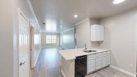 Located at 536 Tenby Drive in Rock Hill, SC, this well-appointed 2-bedroom, 2-bathroom residence offers a thoughtfully designed single-floor layout with a clean, modern aesthetic. The open-concept kitchen is a functional highlight, featuring white shaker-style cabinetry, light quartz countertops, a peninsula with an undermount sink, and black stainless appliances including a range, microwave, and refrigerator. Light wood-look flooring flows through the main living areas, complementing the neutral warm-gray walls and crisp white trim. The living area is spacious and bright, with crown molding accents and access to an outdoor area through a glass-paneled door flanked by a large window, allowing ample natural light. Both bedrooms are generously sized, finished with plush carpet and ceiling fans, offering a comfortable retreat. The primary bedroom includes its own dedicated closet. Each bathroom is finished with wood-look tile flooring, a white vanity with a single sink, a full tub-shower combo, and a large wall mirror with contemporary light fixtures. A dedicated in-unit laundry room houses a full-size washer and dryer with overhead wire shelving, adding practical convenience. Two closets provide additional storage throughout the home.