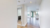 Located on the 9th floor at 150 Keith Rd E in North Vancouver, this two-bedroom, one-bathroom unit offers a well-designed layout with modern finishes throughout. Light wood laminate flooring runs continuously across the living spaces, enhancing the bright and airy atmosphere created by large floor-to-ceiling windows.

The open-concept kitchen features white shaker cabinetry, a glass tile backsplash, quartz countertops, and a full suite of stainless steel appliances including a dishwasher, range, microwave, and refrigerator. A central island provides additional workspace and storage. The living room is generously proportioned, bathed in natural light, and opens directly onto a private balcony with glass railings, offering sweeping views of the North Vancouver cityscape, lush tree canopy, and the waters beyond.

The primary bedroom is a comfortable size and includes mirrored sliding closet doors and direct access to the balcony. The second bedroom also features mirrored closet doors and benefits from natural light. The bathroom is finished with classic white subway tile, polished stone-look floor tile, a dark-toned vanity with ample storage, and chrome fixtures. This unit combines functional design with elevated finishes in a prime North Vancouver location.