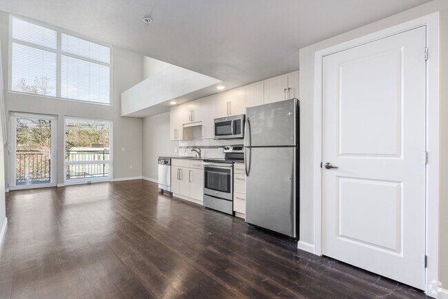 Living room with hardwood floors and a large window. - 1711 12th Apartments