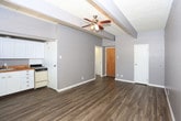 Located at 2601 York Ave in Lubbock, Texas, this single-floor unit offers a practical and well-maintained layout with a clean, neutral aesthetic throughout. Dark wood-look vinyl plank flooring runs continuously across the main living areas, providing a warm contrast to the cool gray walls and crisp white trim.

The open living area is spacious and airy, featuring a ceiling fan with light fixture and a drop tile ceiling with exposed beam detailing. A window unit provides additional climate control, and natural light filters in through a window along the exterior wall, brightening the room.

The kitchen is efficiently designed and accessed through an open partition, keeping it connected to the living space. It is outfitted with white raised-panel cabinetry both above and below the counter, warm butcher block countertops, a single-basin sink, an electric range, and a full-size black refrigerator. Tile backsplash lines the walls behind the counters, adding a clean, classic touch.

The bathroom is bright and neatly appointed, featuring wood-look tile flooring, a white vanity with cabinet storage and a medicine cabinet mirror above, a wall-mounted light bar, and beadboard-style wainscoting along the lower walls. The space feels clean and functional, with a straightforward, practical design throughout the unit.