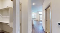 This thoughtfully designed studio offers a bright, open-concept layout that maximizes every square foot. Rich hardwood-style flooring flows seamlessly throughout the main living area, creating a warm and cohesive aesthetic. Large windows and a full-light entry door with transom window flood the space with natural light, while a ceiling fan adds comfort and functionality to the living area.

The kitchen serves as a focal point of the unit, showcasing granite countertops that extend into a peninsula with an undermount sink — ideal for both meal prep and casual dining. Gray shaker-style cabinetry reaches to the ceiling, offering generous storage, and is complemented by a classic subway tile backsplash. Stainless steel appliances, including a refrigerator, range, and microwave, complete the polished look. Geometric pendant lights add a stylish, modern touch overhead.

A double-door closet provides ample storage within the living space. The bathroom is finished with marble-look tile flooring, a granite-topped vanity with gray cabinetry, a framed mirror, and a shower/tub combination — delivering a clean, upscale feel. The entry hallway also includes an additional storage closet. Crisp white walls and recessed lighting throughout give the unit a fresh, contemporary ambiance.