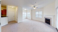 Located at 6134 Chamberlain Pl in Clemmons, North Carolina, this single-floor residence offers a well-organized and comfortable layout with a clean, neutral aesthetic throughout. The spacious living area is carpeted and bathed in natural light from multiple windows, and features a ceiling fan and a tile-surround fireplace, creating a warm and inviting atmosphere. French doors in an adjoining room open to the outside, allowing additional light and outdoor access, while a ceiling fan overhead adds to the room's comfort. The kitchen is outfitted with warm oak cabinetry, dark granite countertops, tile flooring, and black appliances including a range, microwave, and refrigerator. A peninsula counter connects the kitchen to the living space, enhancing the open flow of the floor plan. The bathrooms are finished with tile flooring and clean white fixtures. One bathroom features a pedestal sink and vanity mirror with overhead lighting, while another includes a full tub-shower combination with white tile surround. Soft carpet runs through the main living and bedroom areas, contributing to the overall sense of warmth and ease. Ceiling fans are present in multiple rooms, and neutral wall tones provide a versatile backdrop throughout this well-appointed Clemmons home.
