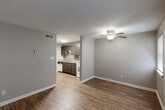 Located in Metairie, Louisiana, this one-bedroom, one-bathroom unit offers a practical and well-appointed single-floor layout. The living room serves as the heart of the space, featuring wood-look plank flooring, neutral gray walls, a textured ceiling, and a ceiling fan with light fixture. Two windows allow natural light to fill the room, complementing the bright, clean aesthetic. The kitchen, open to the living area, is equipped with dark espresso cabinetry, a mosaic tile backsplash, white appliances including a range and dishwasher, and a double-basin sink — providing a functional and visually appealing cooking space. A hallway connects the main living area to the private bedroom, which features plush carpeting, a ceiling fan, a sliding-door closet, and a vertical blind-covered window. The bedroom also provides convenient access to an in-unit laundry area with washer and dryer connections. The bathroom includes a full tub and shower combination with white tile surround, a toilet, and granite-style countertop detailing. Throughout the unit, consistent neutral tones, clean white trim, and ceiling fans in every room contribute to a cohesive and comfortable living environment.