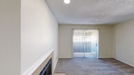 Located at 6424 Iron Horse Blvd in North Richland Hills, TX, this well-appointed one-bedroom, one-bathroom residence offers a comfortable and efficient single-floor layout. The living room serves as the heart of the home, highlighted by a classic tiled fireplace with a white mantle and plush carpeting underfoot. A sliding glass door fitted with vertical blinds fills the space with natural light and provides access to the outdoors. The kitchen stands out as a renovated focal point, featuring sleek gray cabinetry, a mosaic tile backsplash, light stone-look countertops, a double-basin sink, and black appliances including a range and refrigerator. Wood-look flooring runs through the kitchen, adding warmth and contrast. A dedicated laundry area accommodates a full-size washer and dryer alongside an additional refrigerator. The carpeted bedroom is a quiet retreat with a window dressed in horizontal blinds, offering natural light and privacy. The bathroom includes a full tub-shower combination with white tile surround. A textured ceiling is present throughout, and neutral tones across all rooms create a cohesive, clean aesthetic well-suited for everyday living.