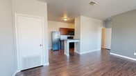 This single-floor, 1-bedroom, 2-bathroom unit offers a practical and comfortable layout designed to maximize every square foot. Rich wood-look flooring flows consistently throughout the space, complemented by neutral gray walls and crisp white trim that lend a clean, modern aesthetic.

The open-concept main area seamlessly connects the living room, dining space, and kitchen, creating a cohesive and functional hub. The kitchen is well-equipped with dark granite-style countertops, rich cherry-toned cabinetry, black appliances including a refrigerator, electric range, and built-in microwave, and a peninsula counter that doubles as a breakfast bar. A dedicated pantry provides additional storage just steps from the kitchen.

Natural light filters into the living area through windows flanking the front entry door, brightening the space and offering views of the outdoors. The bedroom features soft blue-gray walls and continues the wood-look flooring, with access to multiple closets for ample storage. 

Two bathrooms serve the unit, each featuring dark vanity cabinetry with granite-style countertops and a mirrored vanity. One bathroom includes a full soaking tub and shower combination. Three closets throughout the unit ensure generous storage capacity, rounding out this efficiently designed and well-finished residence.