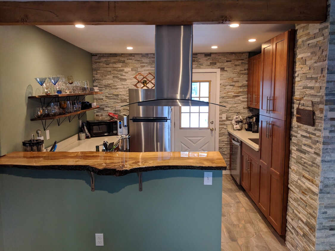 Gorgeous NW inspired kitchen with live edge bar, induction stove, open shelving and rock walls! - 2909 NE 6th St