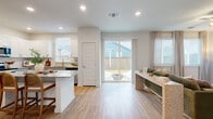 This two-story home offers a thoughtfully laid-out floor plan spread across two levels. The main floor features an open-concept kitchen and living area bathed in natural light, with light hardwood-style flooring flowing throughout. The kitchen is well-appointed with white upper shaker cabinets, grey lower cabinets, granite countertops, stainless steel appliances, a subway tile backsplash, and a central island. The adjacent living room is bright and welcoming, with large windows and a sliding glass door that opens directly to the backyard, creating a seamless indoor-outdoor connection. A convenient half bathroom with a pedestal sink and oval mirror completes the main level. The backyard is fully fenced with a wood panel privacy fence and includes a patio area with a fire pit, ideal for outdoor entertaining. Upstairs, three bedrooms offer comfortable retreats, each featuring plush carpet flooring, natural light from well-positioned windows, and clean, neutral finishes. The primary bedroom provides a generous amount of space. Two full bathrooms serve the upper level, one featuring a granite-topped vanity with grey cabinetry. A staircase and hallways connect both floors efficiently, contributing to the home's practical and functional layout throughout.