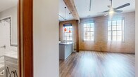 Located at 330 E Ninth St in Saint Paul, Minnesota, this loft-style unit showcases a compelling blend of industrial heritage and modern finishes. The space is defined by its exposed yellow brick walls, which stretch across multiple rooms and lend a warm, textured character throughout. Original heavy timber beams and structural columns add to the historic charm, while rich hardwood flooring runs seamlessly underfoot.

The open-concept living areas benefit from abundant natural light streaming through large, multi-pane windows that frame views of the surrounding urban neighborhood. Two living areas offer flexible use of space, each anchored by the striking brick backdrop.

The kitchen is a standout feature, centered around a granite-topped island with a built-in sink and pendant lighting overhead. White shaker cabinetry, stainless steel appliances — including a refrigerator, range, and microwave — and exposed ductwork overhead complete the contemporary-industrial aesthetic. In-unit stacked laundry is also conveniently included.

The bathroom is finished with basket-weave tile flooring, a combination tub and shower with decorative tile accents, and a vanity with classic styling, accessed through rich wood-framed doors. Throughout the unit, the interplay of raw architectural elements and updated finishes creates a distinctive and cohesive urban living environment.