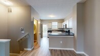 Located at 6460 Chelsea Glen Dr in Columbus, Ohio, this three-story home offers a practical and well-organized layout across its floors. The ground level features an attached garage with a motorized door opener, concrete flooring, and direct interior access — providing secure and convenient parking or additional storage space. The main living level serves as the heart of the home, where an open-concept kitchen and living room create a cohesive, functional space. The kitchen is equipped with stainless steel appliances, including a full-size refrigerator, and includes a dedicated nook housing a stacked washer and dryer for in-unit laundry convenience. Light wood-look flooring flows throughout this level, complemented by neutral warm-toned walls and natural light from windows with blinds. The upper floor houses both bedrooms and two full bathrooms. The generously sized primary bedroom offers carpeted flooring and ample natural light. The second bedroom also features carpet and multiple windows. Both bathrooms are well-appointed with white vanities, wood-look flooring, and clean, neutral finishes — one featuring a walk-in glass shower and the other a tub/shower combination. Staircases connect all three levels, making this home an efficient and comfortable multi-floor residence.