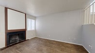 This two-story home offers a practical and comfortable layout spread across two floors of similar size. The main level features an open living room with warm wood-look flooring, a textured ceiling, and a classic wood-framed fireplace with vertical shiplap surround — a standout focal point of the space. Natural light filters in through window blinds, creating a bright and welcoming atmosphere. Adjacent to the living area, the galley-style kitchen is well-equipped with dark cabinetry, black appliances including an electric range and refrigerator, a double sink, and a window that brings in additional natural light. A hallway and closets provide added storage convenience on the main level, along with a bathroom featuring a vanity with dark cabinetry and a lighted mirror. Upstairs, two bedrooms offer plush carpeting and generous natural light through large windows. The primary bedroom connects directly to a private bathroom and includes a sliding glass door leading to a private balcony with outdoor views. A second full bathroom with wood-look flooring and a clean, neutral vanity serves the additional bedroom. Three bathrooms in total ensure convenience throughout. Staircases connect both levels, and the neutral color palette throughout lends the home a clean, move-in-ready feel.