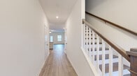 This two-story home offers a thoughtfully designed layout spread across two floors, providing comfortable living for everyday life. The main level features an open-concept kitchen and living room area, where the kitchen stands out with crisp white shaker cabinets, granite countertops, a classic subway tile backsplash, and stainless steel appliances. The living room is bright and airy, benefiting from multiple windows and a ceiling fan, with a glass-panel door providing additional natural light. Light hardwood-style flooring flows throughout both levels, creating a clean, cohesive aesthetic. A hallway on the main floor connects key spaces, with a staircase featuring a white baluster railing and warm wood handrail leading to the upper level. The upper floor houses all three bedrooms, including a generously sized primary bedroom distinguished by a tray ceiling with crown molding and a ceiling fan. The additional bedrooms are well-proportioned and naturally lit via windows with views of the surrounding greenery. The two bathrooms are finished with elegant marble-look tile flooring, white vanities, and glass-enclosed showers. A dedicated laundry room with washer and dryer hookups and built-in shelving adds everyday convenience. Closets and hallways round out the practical layout of this move-in-ready home.