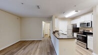 This efficiently designed 1-bedroom, 1-bathroom unit is laid out across a single floor, offering a practical and comfortable living environment. Light-toned luxury vinyl plank flooring flows consistently throughout all rooms, creating a cohesive and clean aesthetic.

The open-concept kitchen and living area forms the heart of the unit. The kitchen features white cabinetry, dark granite-style countertops, a peninsula with a sink, and a full suite of stainless steel appliances including a refrigerator, electric range, microwave, and dishwasher. A pendant light fixture accents the peninsula. The adjoining living area is bright and open, with a glass-panel exterior door and adjacent window that invite natural light and outdoor views.

The bedroom is a comfortable and well-proportioned room, featuring a ceiling fan with light fixture, a large window with blinds offering additional natural light, and a dedicated closet. The neutral, warm beige walls carry throughout the unit, contributing to an airy, welcoming atmosphere.

The bathroom is appointed with white cabinetry, dark countertops, a full-size tub and shower combination, and wood-look flooring that continues the unit's design language. Additional spaces include a utility room and a textured ceiling in select areas, rounding out this functional and move-in-ready unit.