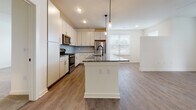 Located at 2500 Gault Way Dr in Summerville, South Carolina, this single-floor residence offers a thoughtfully designed open-concept layout that seamlessly connects the kitchen, dining, and living areas. The kitchen is a standout feature, equipped with stainless steel appliances including a refrigerator, range, and microwave, complemented by crisp white cabinetry, a herringbone-patterned tile backsplash, and granite countertops. A central island with pendant lighting and an integrated sink serves as both a functional workspace and a natural gathering point. Warm wood-look flooring flows throughout the main living areas, while the bedrooms are finished with plush carpeting and feature ceiling fans and ample natural light through large windows with blinds. The bathrooms are finished with granite-topped vanities, wood-look flooring, and full tub-shower combinations with white tile surrounds. The overall design palette is clean and neutral, with white walls and trim creating a bright, welcoming atmosphere throughout. The open floorplan, as seen in the dollhouse view, ensures a connected and functional flow between all areas of the home.