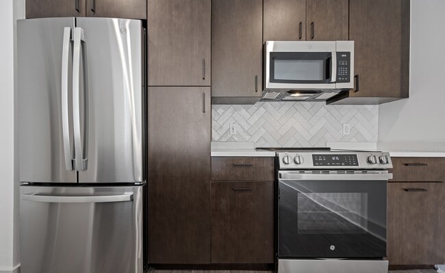 Sleek Kitchen Design with Stainless Appliances and Dark Wood Cabinets - The Landing at Vinnin Square