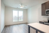 Located at 575 Zor Shrine Pl in Madison, WI, this 1-bedroom, 1-bathroom unit offers a compact yet efficiently organized single-floor layout. The open-concept kitchen and living area serves as the heart of the unit, showcasing dark espresso-toned cabinetry, a white subway tile backsplash, and a full suite of stainless steel appliances including an electric range, built-in microwave, dishwasher, and refrigerator. A freestanding kitchen island with a crisp white countertop and built-in shelving provides additional prep and storage space. Light hardwood-style flooring runs throughout the main living area, complemented by a ceiling fan and a large window that allows natural light to fill the space with views of the surrounding area. The bedroom offers a comfortable footprint finished with soft carpeting and a vertical window. An attached walk-in closet features built-in shelving units and dual hanging rods, providing ample and well-organized storage. The bathroom includes a full soaking tub and shower combo with matte black fixtures, a single-sink vanity with dark cabinetry, and light wood-style tile flooring. A hallway connects the rooms, completing this clean and modern layout.