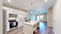 Located at 300 Perigon Dr in Palm Coast, Florida, this well-appointed 3-bedroom, 2-bathroom single-floor residence offers a clean, modern aesthetic throughout. The open-concept kitchen and living area serves as the heart of the home, featuring sleek white cabinetry, stainless steel appliances, a subway tile backsplash, quartz countertops, and a large center island with pendant lighting — ideal for both cooking and casual dining. Hardwood-style flooring runs through the main living areas, adding warmth and continuity to the space. The living room benefits from a ceiling fan, a glass door, and a window that allows natural light to pour in and provides outdoor views. The generously sized primary bedroom features plush carpeting and a double-door closet, while additional bedrooms also offer carpet flooring, ceiling fans, and windows with natural light. The primary bathroom is outfitted with a glass-enclosed walk-in shower with marble-style tile surround, wood-look flooring, and a modern vanity. The second bathroom mirrors the clean design with a tub-shower combo, a streamlined vanity, and wood-look flooring. A utility room and dedicated hallway complete the thoughtfully organized layout of this inviting Florida residence.